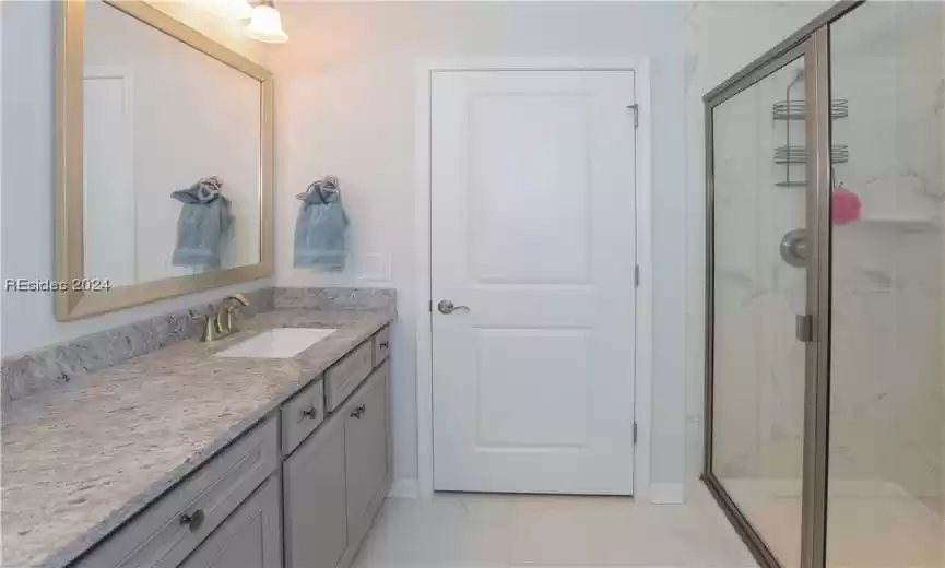 Primary Bathroom showing the tiled walk-in shower with glass door and bench seat and tile flooring
