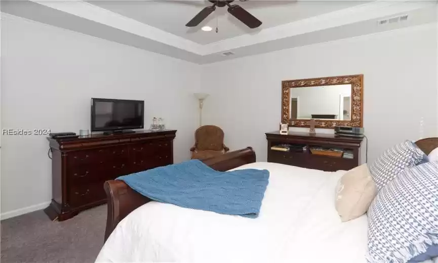 Primary bedroom featuring a tray ceiling with ornamental molding