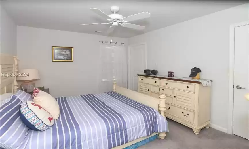 Carpeted bonus bedroom upstairs featuring ceiling fan
