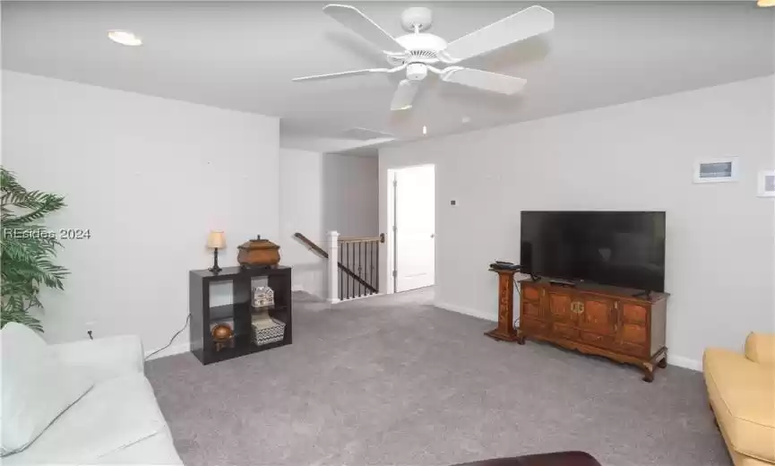 Living room featuring carpet, can lights and ceiling fan.  The door leads to bedroom 3 which has an ensuite bathroom and a walk-in closet.