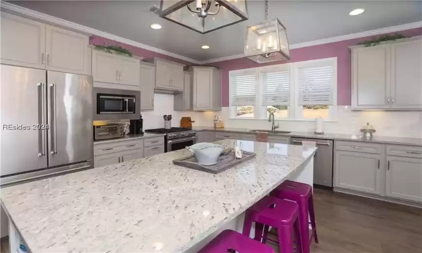 The upgraded Chef's Kitchen has premium Stainless Steel appliances, a huge island for casual snacks/meals, subway tile backsplash, manufactured wood floors, and seeded glass, upgraded, pendant lighting