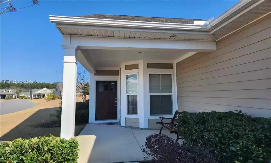 Property entrance featuring a porch with room for a bench to sit with friends to chat.
