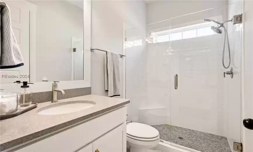 Downstairs full bath between bedrooms with frameless shower doors