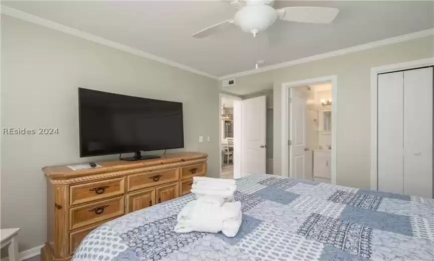 Bedroom featuring a closet, ceiling fan, ornamental molding, and ensuite bathroom