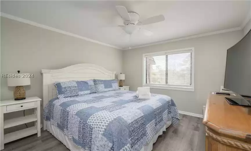 Bedroom with ceiling fan, ornamental molding, and dark hardwood / wood-style floors