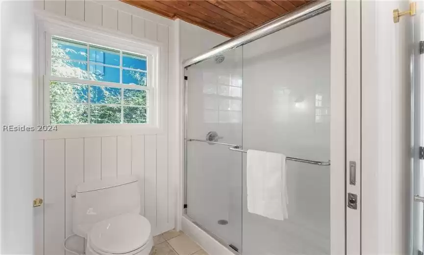 Bathroom with a shower with door, tile flooring, wooden ceiling, and toilet