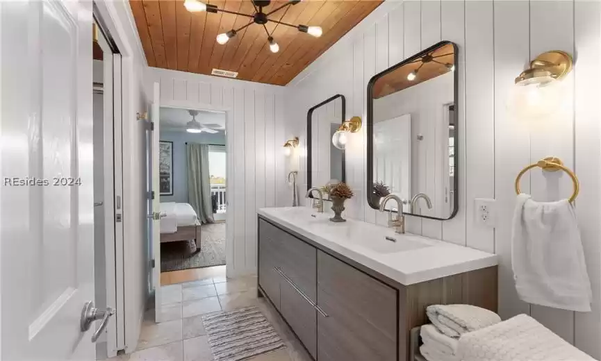 Bathroom featuring double sink vanity, ceiling fan, wooden ceiling, wood walls, and tile flooring