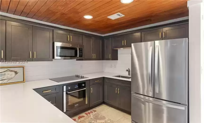 Kitchen with sink, dark brown cabinetry, backsplash, appliances with stainless steel finishes, and wood ceiling