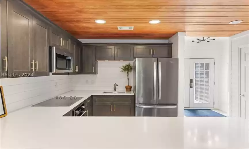 Kitchen with sink, tasteful backsplash, dark brown cabinetry, appliances with stainless steel finishes, and wood ceiling