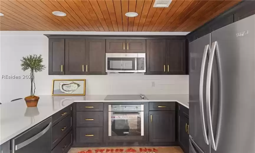 Kitchen with appliances with stainless steel finishes, dark brown cabinetry, and wood ceiling