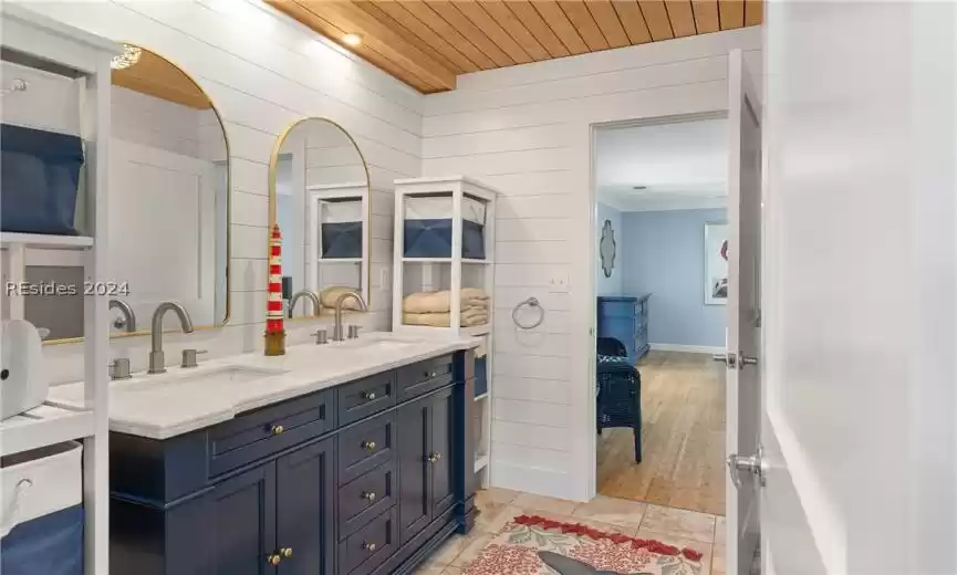 Bathroom featuring tile flooring, crown molding, wood ceiling, and dual vanity