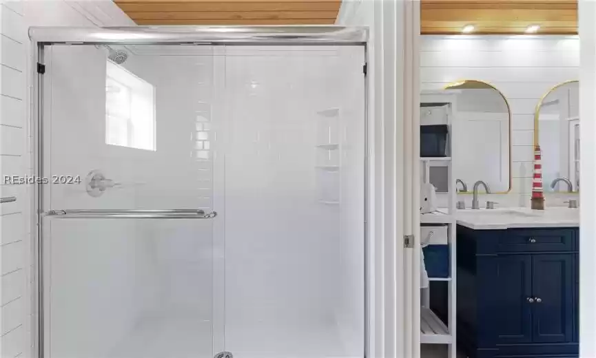 Bathroom featuring large vanity and a shower with door