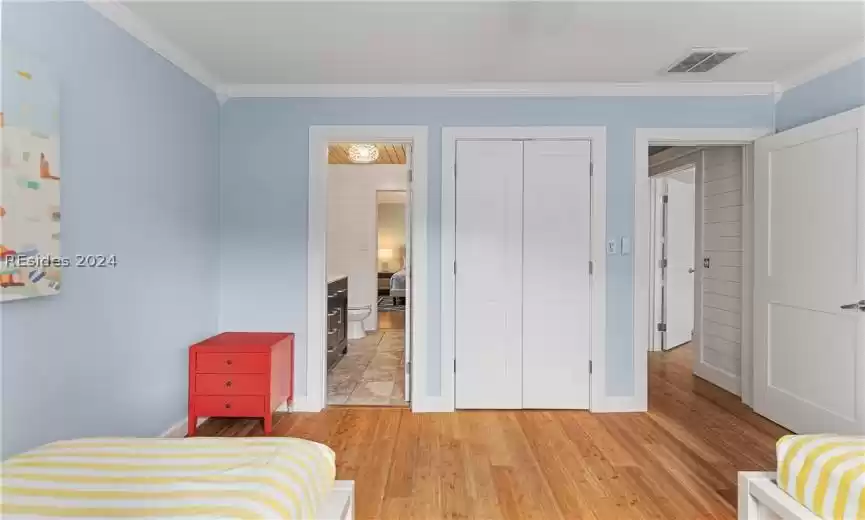 Bedroom featuring ornamental molding, light wood-type flooring, a closet, and ceiling fan