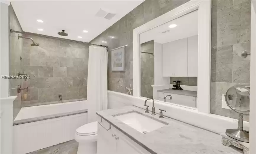 Full bathroom featuring shower / tub combo with curtain, oversized vanity, tile walls, toilet, and tile floors