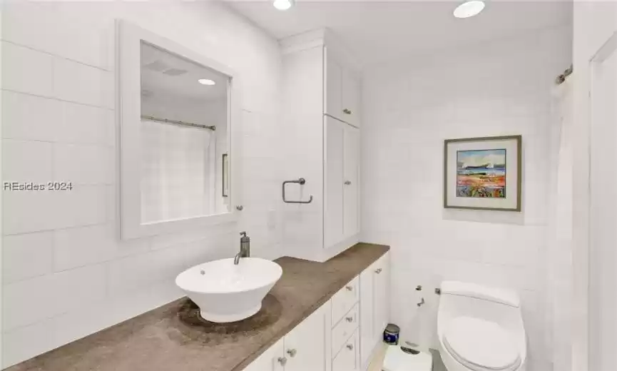 Bathroom featuring tasteful backsplash, toilet, tile walls, and vanity with extensive cabinet space