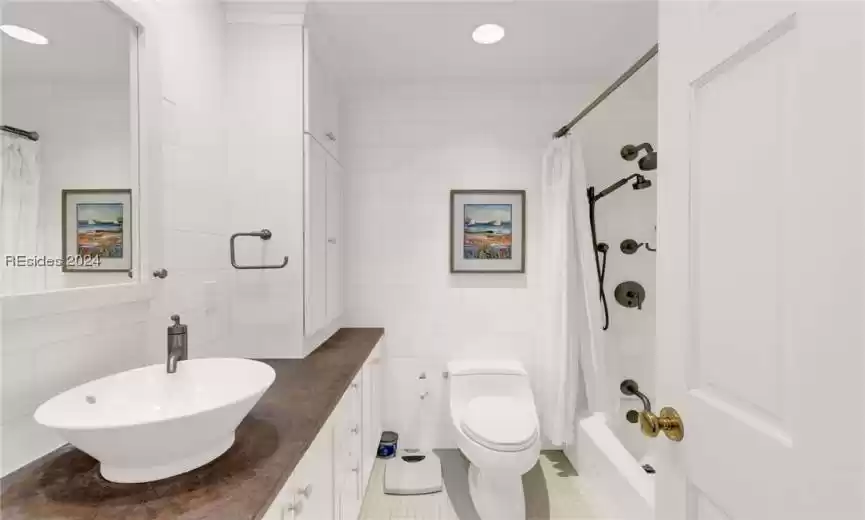 Full bathroom with shower / bath combo, oversized vanity, toilet, tile floors, and tile walls