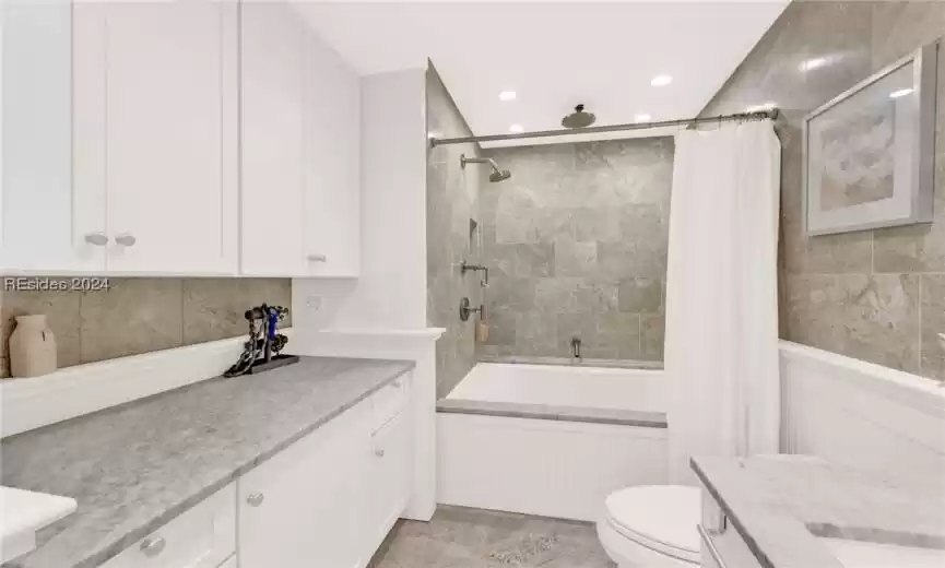 Full bathroom featuring vanity, shower / tub combo with curtain, tile walls, toilet, and tile flooring