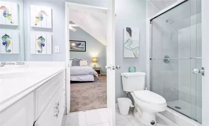 Bathroom with vanity, a shower with door, toilet, and tile floors