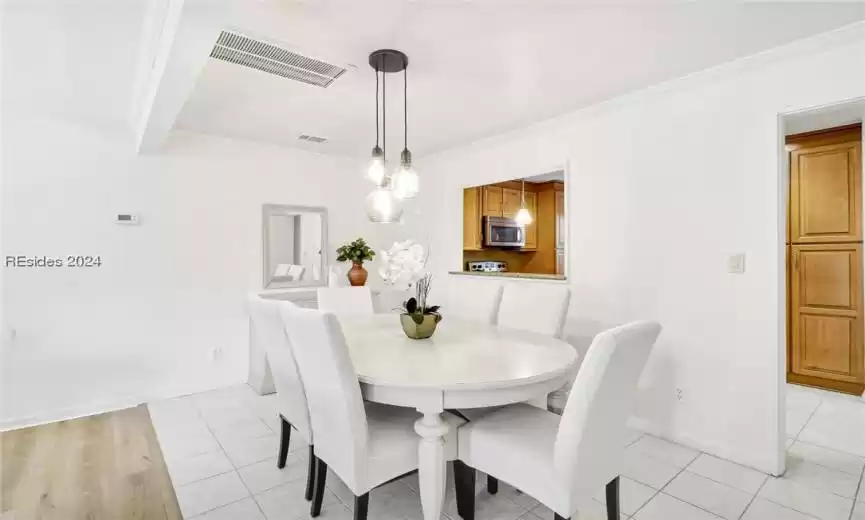 Dining area with ornamental molding and light wood-type flooring