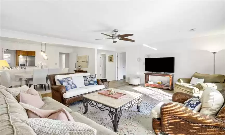 Living room with ceiling fan, ornamental molding, and light wood-type flooring