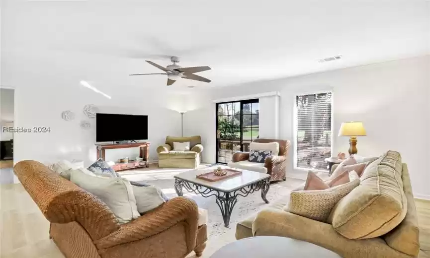 Living room with light wood-type flooring, ceiling fan, and ornamental molding