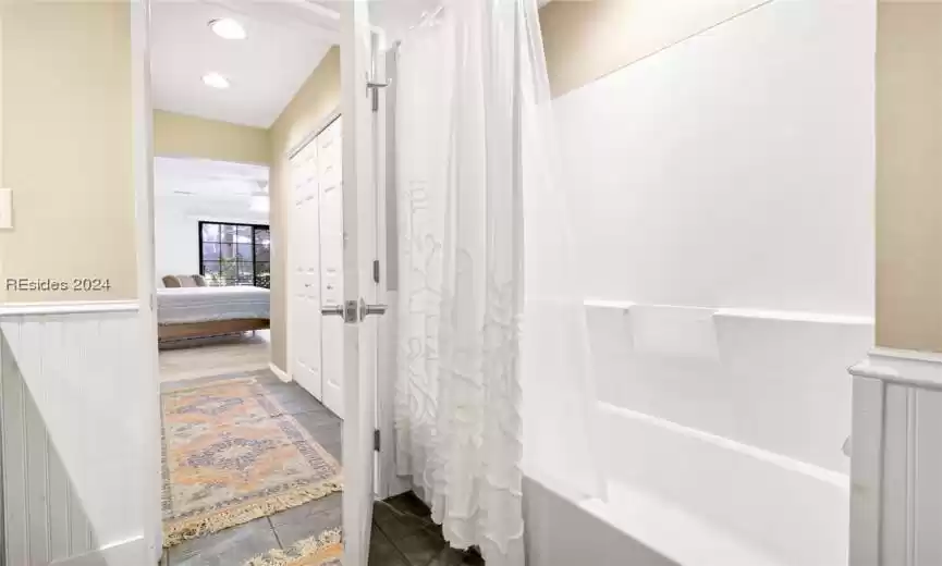 Primary Bathroom with shower / bathtub combination with curtain, ceiling fan, and tile flooring