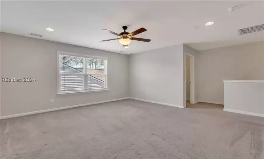 Large great room, also known as the loft, on the second floor featuring wall to wall carpet with lighted ceiling fan and recessed lights