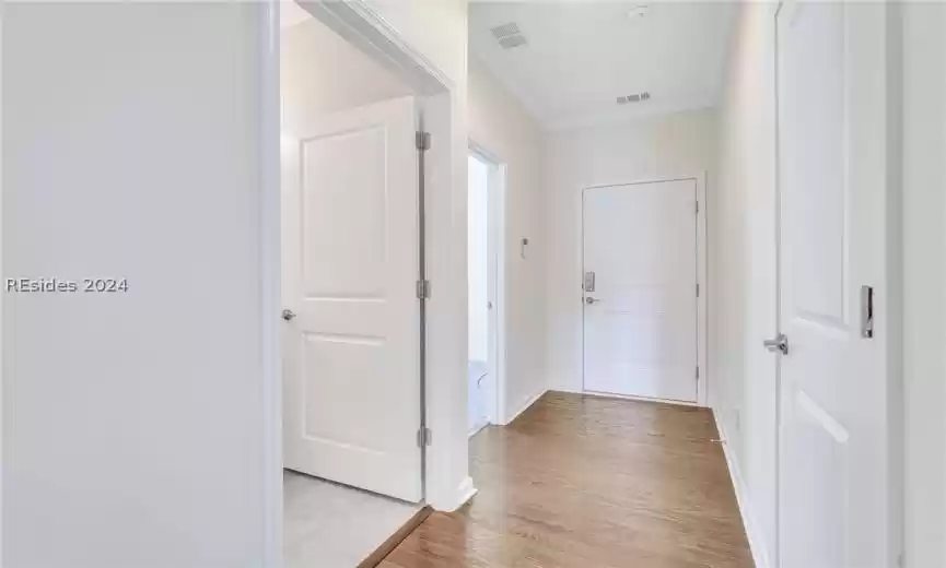 Hallway to first floor guest area and garage with wood-type flooring