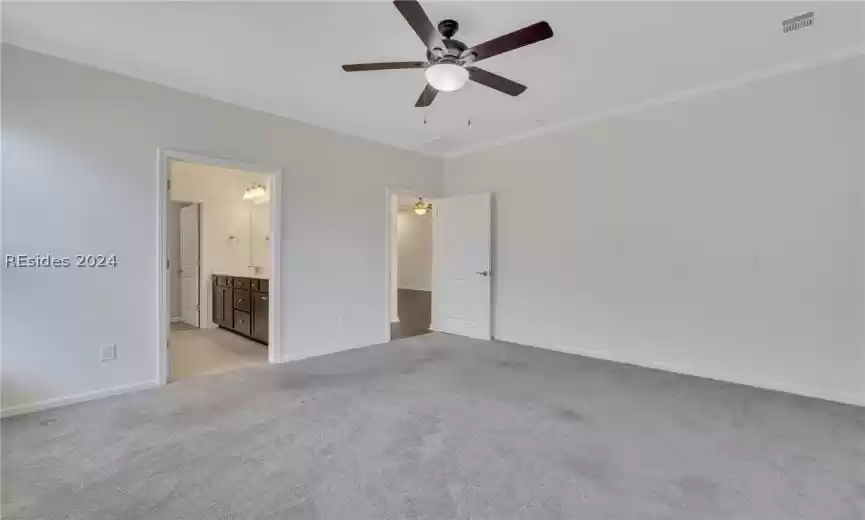 Primary bedroom with crown molding, light carpet, and ceiling fan