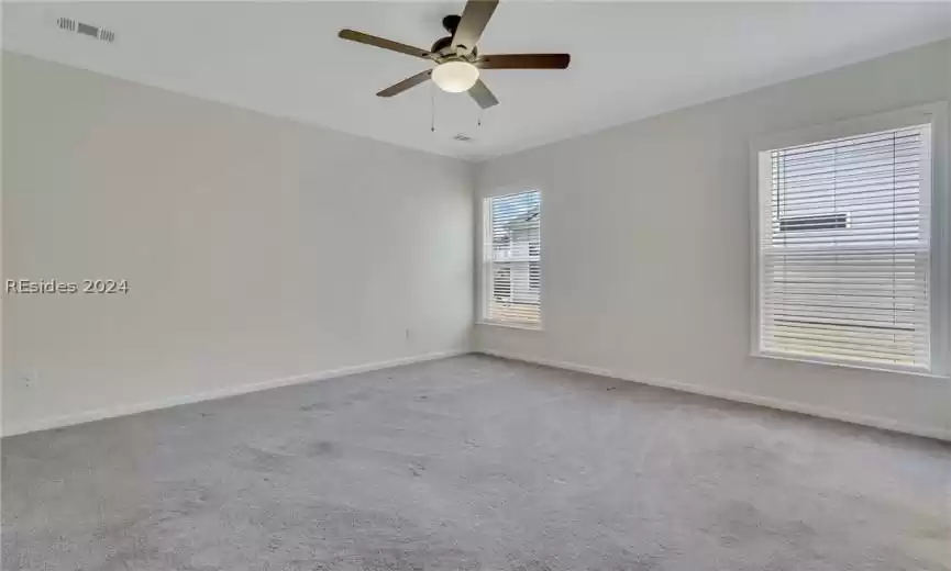 Primary bedroom featuring crown molding, light carpet, and lighted ceiling fan