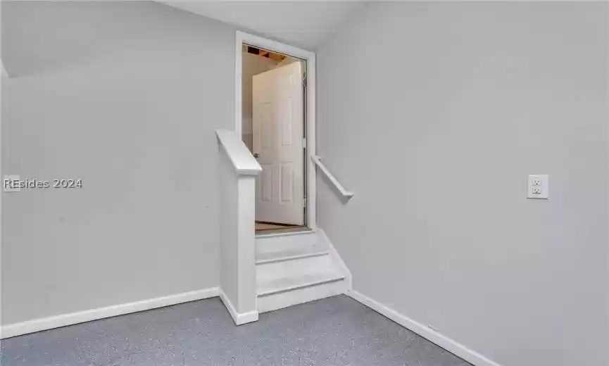 Garage view of entry door to permanent stairs leading to storage area over the garage