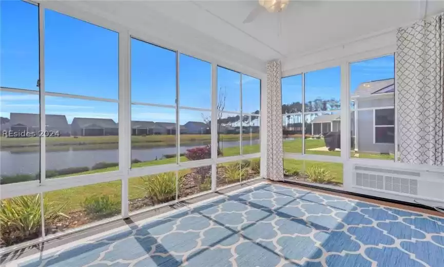 Four season room featuring ceiling fan, hvac unit and a water view