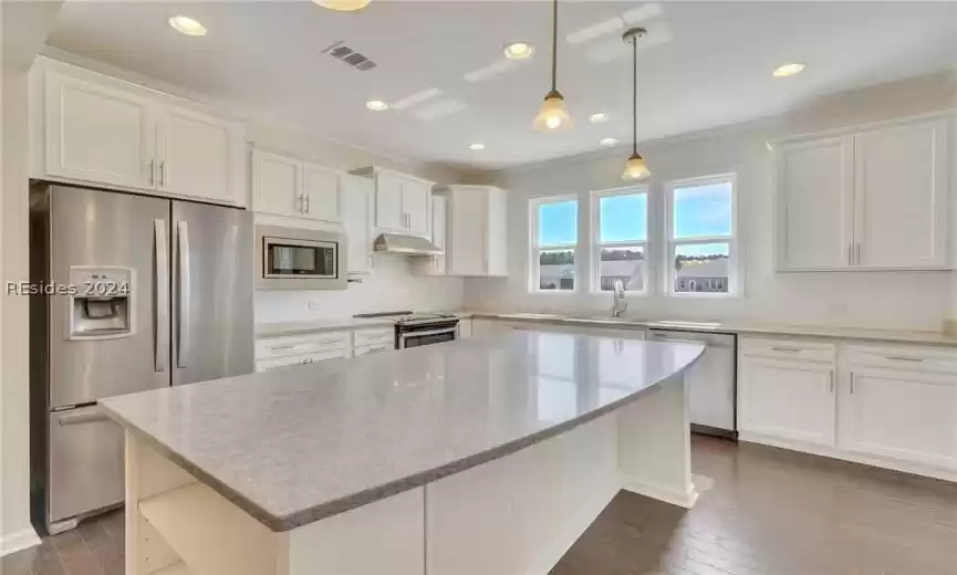 Kitchen with appliances with stainless steel finishes, a center island which will accommodate breakfast bar stools, and pendant lights