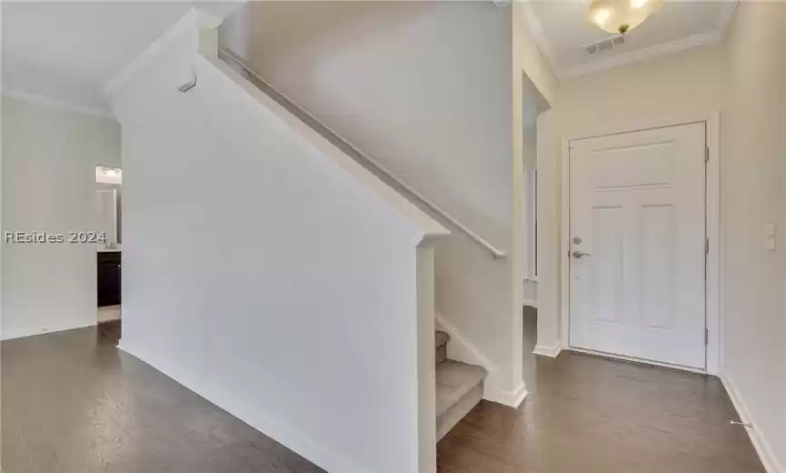 Entryway with dark wood-type flooring and crown molding