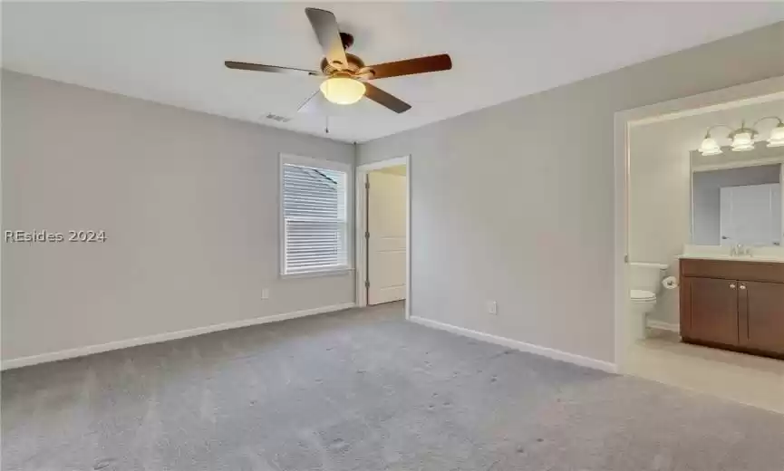 second story/loft bedroom with ensuite bathroom, light carpet and ceiling fan