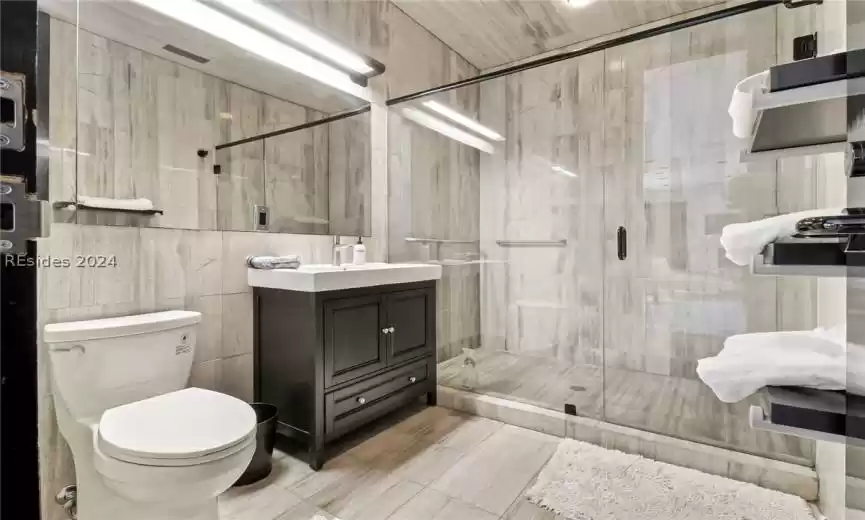 Bathroom with vanity, tile flooring, tile walls, and toilet