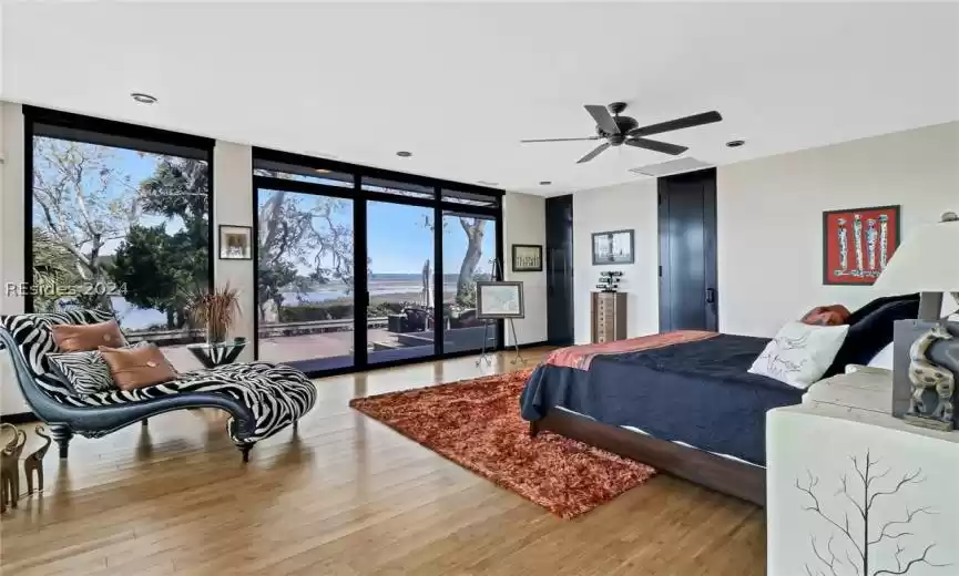 Bedroom featuring light hardwood / wood-style flooring, a wall of windows, access to outside, and ceiling fan
