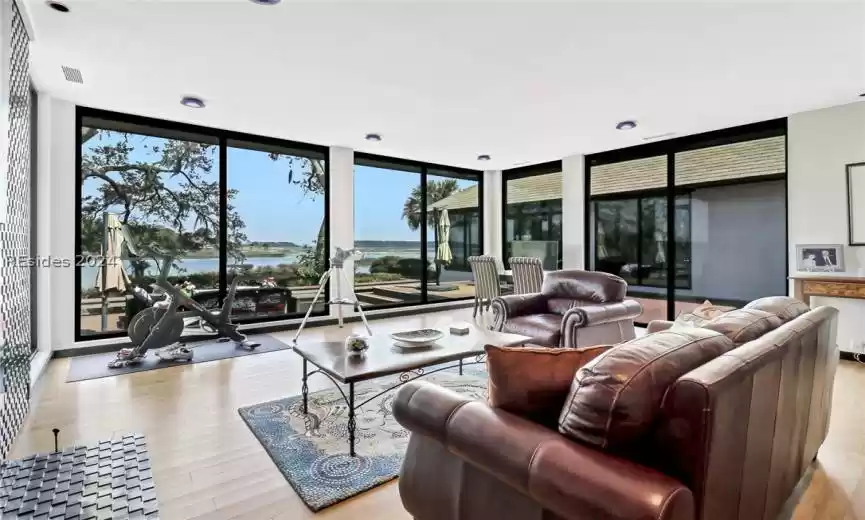 Living room with floor to ceiling windows, light wood-type flooring, and a water view