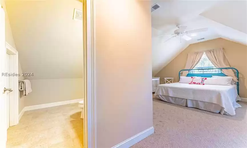 Bedroom featuring light tile flooring, lofted ceiling, and ceiling fan
