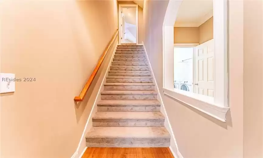 Staircase with light hardwood / wood-style flooring, ornamental molding, and washing machine and clothes dryer