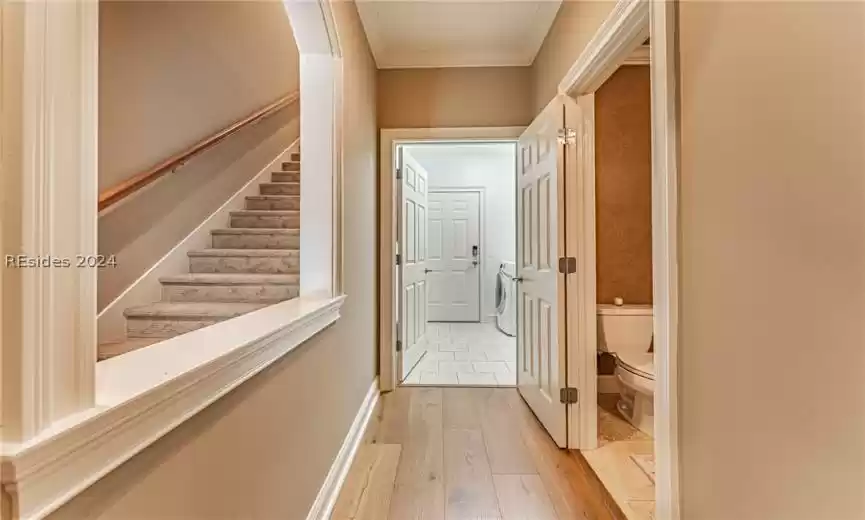 Hall with ornamental molding, light hardwood / wood-style flooring, and washer / clothes dryer