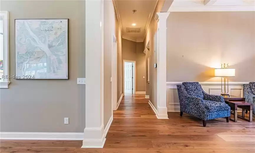 Corridor featuring decorative columns, crown molding, and hardwood / wood-style floors