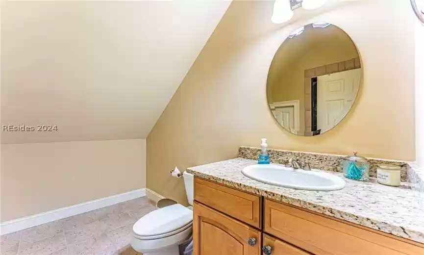 Bathroom featuring tile floors, toilet, lofted ceiling, and oversized vanity