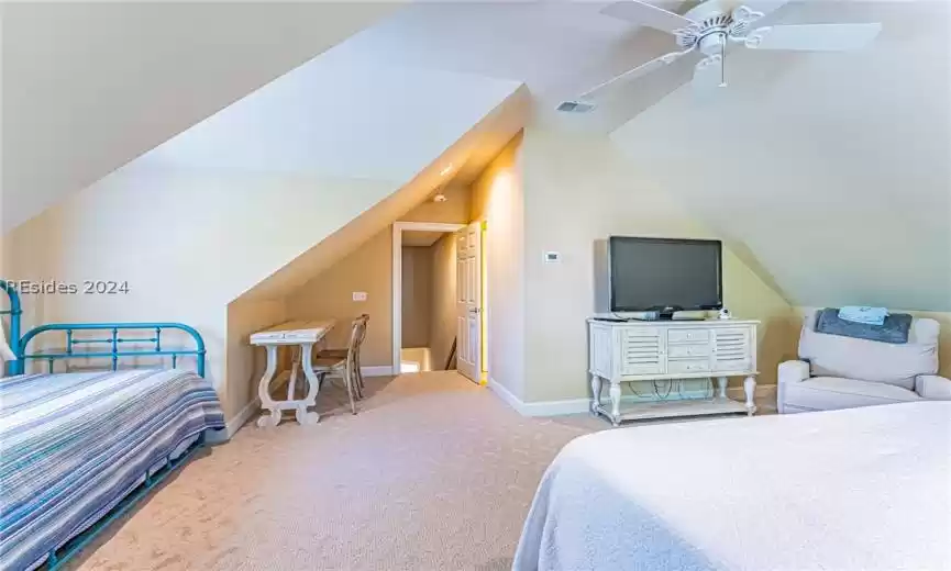 Carpeted bedroom featuring vaulted ceiling and ceiling fan