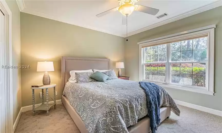 Carpeted bedroom with ornamental molding and ceiling fan