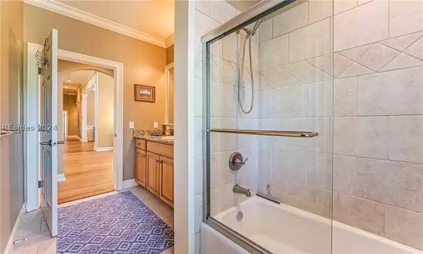 Bathroom with combined bath / shower with glass door, vanity, crown molding, and tile flooring