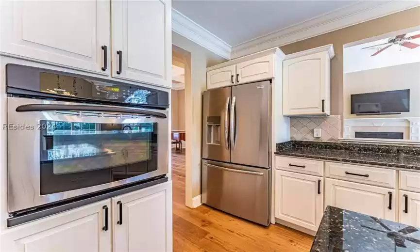 Kitchen with white cabinetry, tasteful backsplash, light hardwood / wood-style floors, stainless steel appliances, and ceiling fan