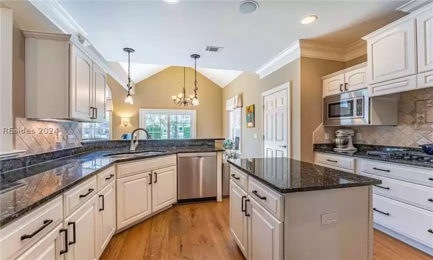 Kitchen with an inviting chandelier, backsplash, stainless steel appliances, and light hardwood / wood-style floors