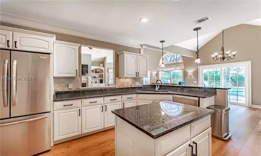 Kitchen featuring a notable chandelier, sink, backsplash, a kitchen island, and stainless steel appliances