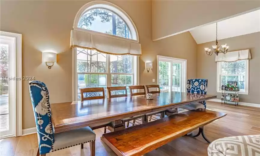 Dining area featuring a chandelier, light wood flooring, plenty of natural light, and high vaulted ceiling